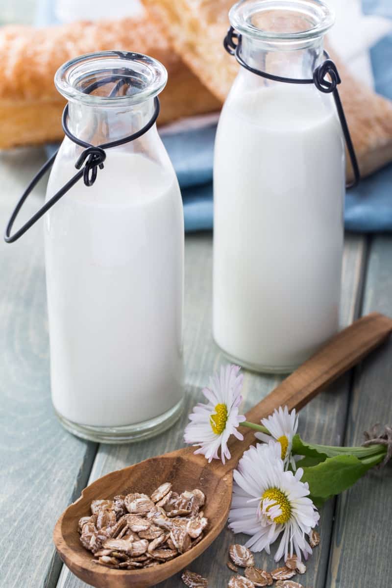 Bottles of local milk, spoonful of oats, and flowers on a table