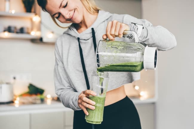 a woman preparing a smoothie for post-workout recovery